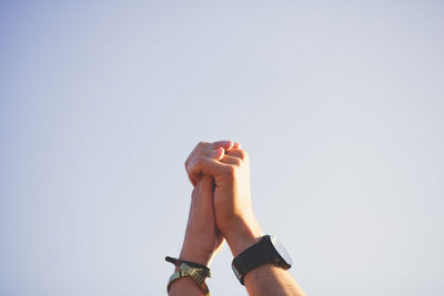 Couple holding hands against clear sky