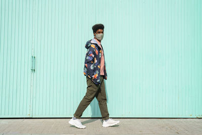 Full length portrait of young man standing against wall