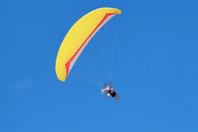 Low angle view of person paragliding against clear blue sky