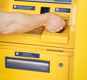 Low angle view of hand holding yellow mailbox