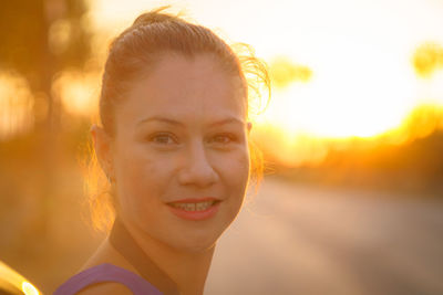 Close-up portrait of smiling young woman on road during sunset