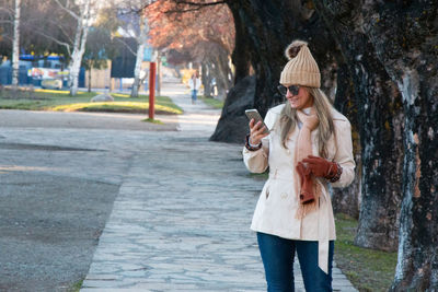 Full length of young woman using smart phone in city