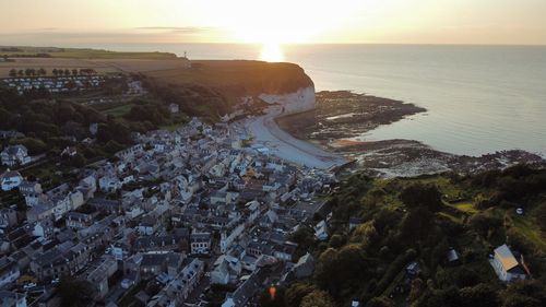 Aerial view of townscape by sea against sky at sunset