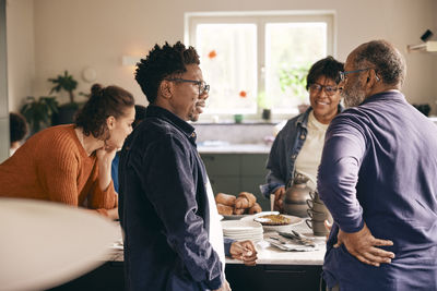 Multigenerational family talking with each other while standing in kitchen at home