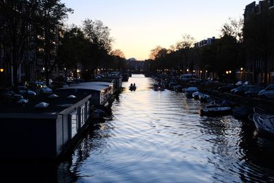 Canal amidst trees against sky during sunset