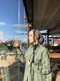 Young woman standing by window at store