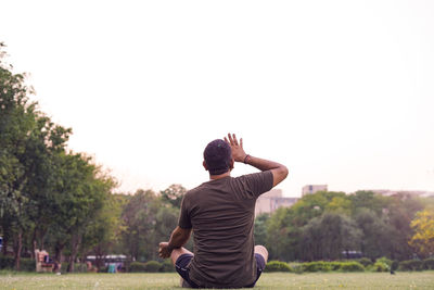 Rear view of man standing on field against clear sky