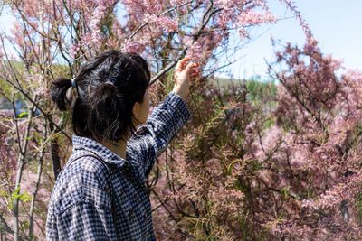 Midsection of woman by cherry tree in forest
