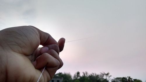 Close-up of person holding hands against sky