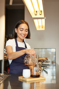 Portrait of smiling young woman holding coffee on table