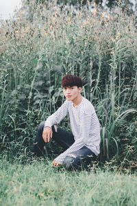 Portrait of young man kneeling against plants