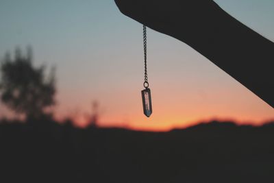 Close-up of silhouette hanging against sky at sunset