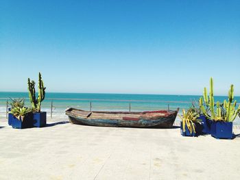 Boats on beach against clear blue sky