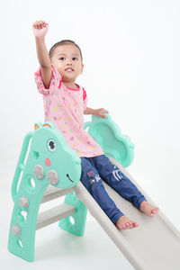 Portrait of cute girl playing with toys against white background