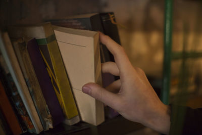 Close-up of hand removing book from shelf