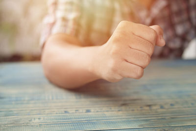 Close-up of man clenching fist on table