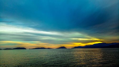 Scenic view of sea against dramatic sky during sunset