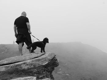 People with dog on mountain against sky