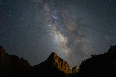 Low angle view of star field and mountains against sky at night