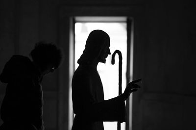 Side view of silhouette man and woman standing against window