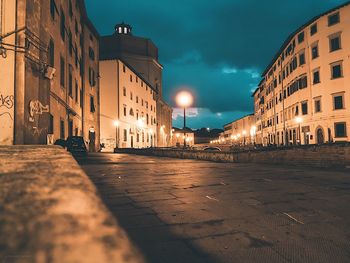 Illuminated street amidst buildings in city at night