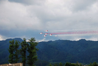 Low angle view of airplane flying over mountains against sky