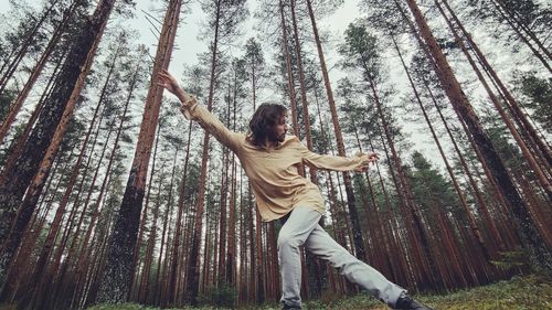 Low angle view of person against trees in forest