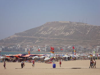 Group of people on beach against clear sky