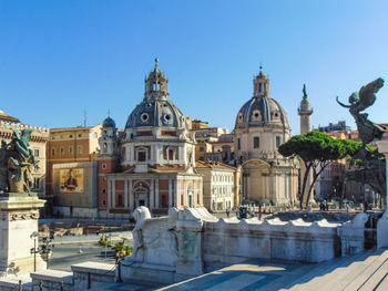 Buildings in city against clear blue sky