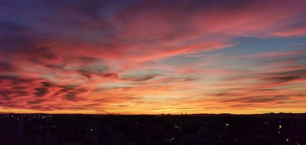 Silhouette buildings against dramatic sky during sunset