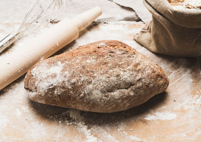 Baked oval rye flour bread in a metal baking sheet on the table, top view