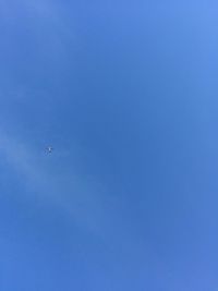 Low angle view of airplane flying against clear blue sky