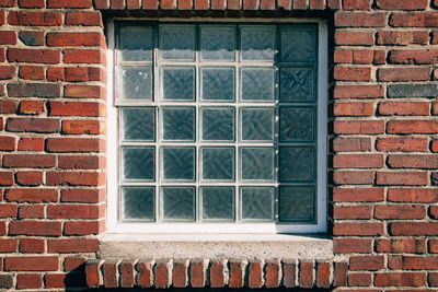 Blue glass block window in red brick wall