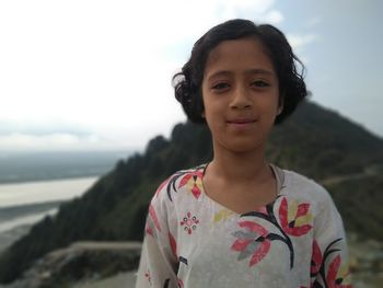 Portrait of smiling girl standing on mountain against sky