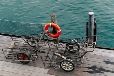 High angle view of a lifebelt and two handcarts on a railing