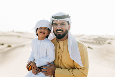 Father and son enjoying while kneeling in desert