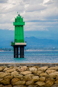 Lighthouse by sea against sky