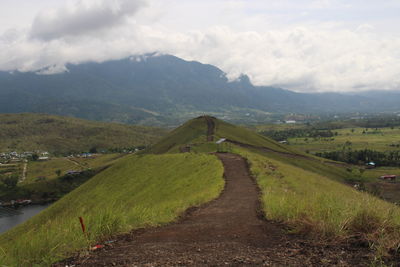 Road amidst green landscape against sky