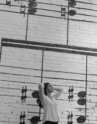 Rear view of woman with umbrella against wall