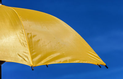 Close-up of yellow umbrella against clear blue sky