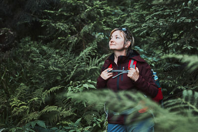 Woman with backpack hiking in forest, actively spending summer vacation close to nature