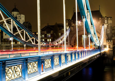 Illuminated bridge over river in city at night