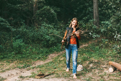 A tourist girl in nature collects firewood for a fire. a woman in close-up. the concept of travel