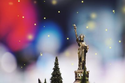 Close-up of statue against illuminated christmas tree