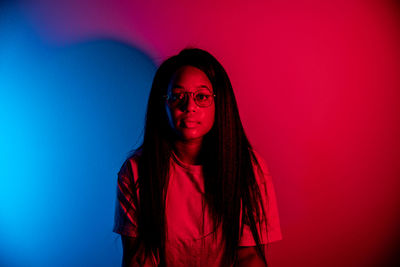 Portrait of woman standing against red background