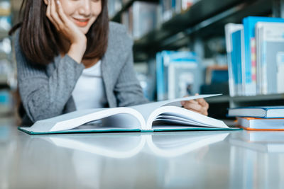 Midsection of woman reading book while sitting on table