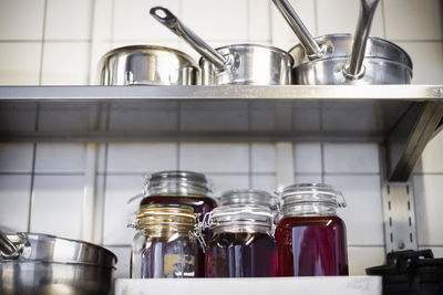 Jars and utensils on shelf at restaurant kitchen