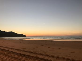 Scenic view of beach against clear sky during sunset