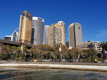 Buildings by swimming pool in city against blue sky