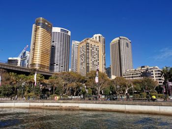 Buildings by swimming pool in city against blue sky